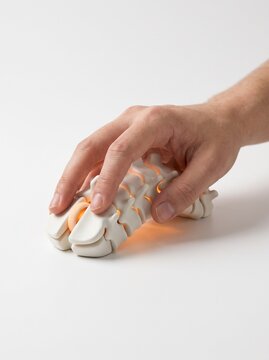 Male hand clicking ergonomic computer mouse shaped like human spine bones with warm glow, office syndrome concept