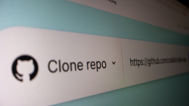 A close up view of a computer monitor displaying a github url in a browser address bar with clone repo text.