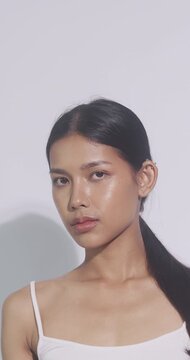 Beautiful Asian woman blocking light and smiling at camera. Happy female model showing clear smooth skin.