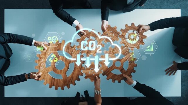 A diverse business team collaborates around a table, using gears and digital elements to symbolize commitment to sustainability and reduction of carbon emissions in a modern office. Raster