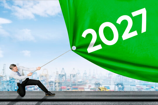 Businessman Pulling Big Green 2027 Banner with Chain at Industrial Port