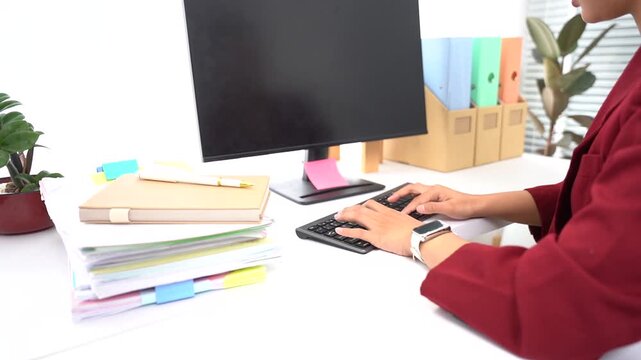 Office Productivity: A focused individual works diligently at a desk, typing on a keyboard with stacks of documents nearby, symbolizing dedication to tasks and workflow.
