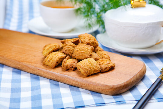 Traditional crispy cookies with teacup on checkered tablecloth