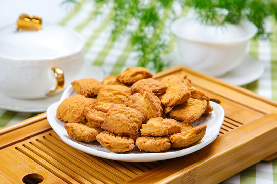 Traditional crispy cookies with teacup on checkered tablecloth