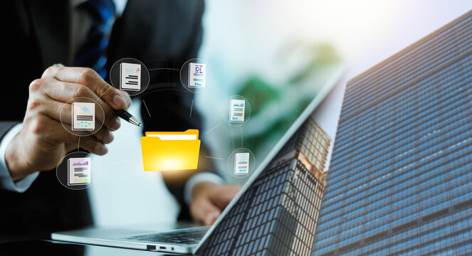 Business person working on a laptop with a digital folder and file management network icons against a modern city background. Concept of enterprise document management and corporate data workflow.