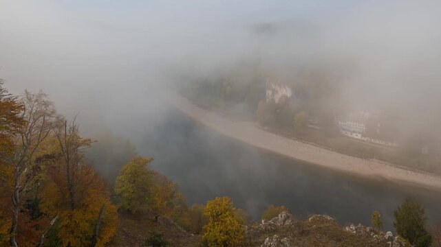 Time lapse of moving fog over Danube river in Lower Bavaria in autumn with colorful foliage trees