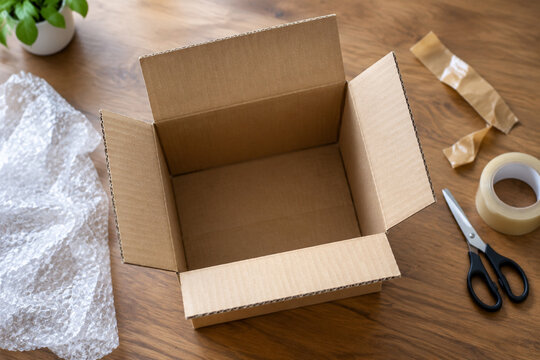 Top-down view of opened cardboard shipping box with tape and scissors.