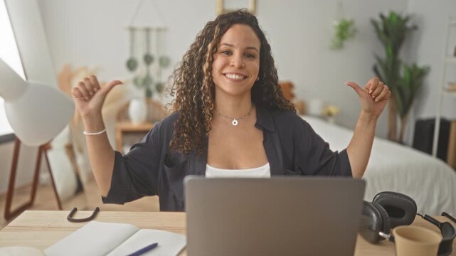 Woman at laptop smiling and pointing thumbs to herself while seated at a desk in a building; confidence remote work productivity.