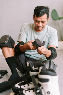Person preparing protective gear for inline skating indoors