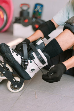 Person preparing for inline skating by putting on protective gear and rollerblades