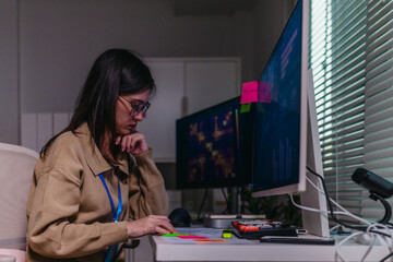 Obraz na płótnie Canvas Female data scientist analysing machine learning results on computer screen in office at night