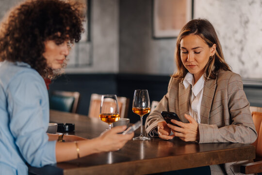 Women phubbing, ignoring each other at restaurant