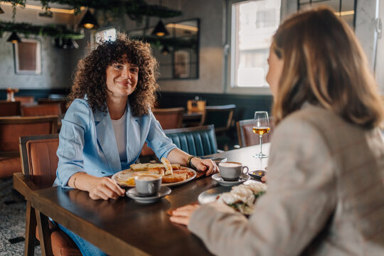 Smiling woman enjoying breakfast with friend in restaurant