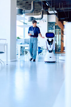 Businessman collaborating with an AI robot in a modern office, symbolizing innovation, future technology, and automation in business