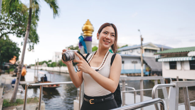 Solo female traveler enjoy travel local river settlement community taking photo by digital camera