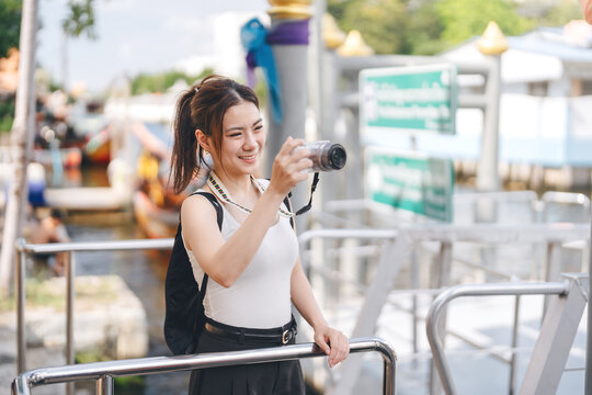 Solo female traveler enjoy travel local river settlement community taking photo by digital camera
