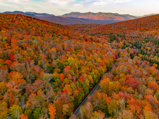 Fototapeta premium Aerial view of road in colorful autumn mountain forest during sunset