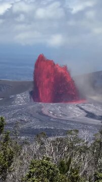 Vibrant red lava erupts explosively from a volcano crater with smoke