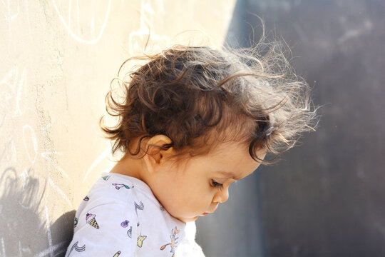 Toddler with messy curly hair looking down.