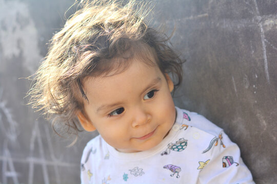 Toddler with curly messy hair smiles.