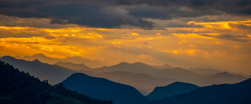 Banner Dramatic sunset mountain landscape. Dawn sky gold dusk time cloudscape with sunlight. Panorama Amazing Beautiful landscape hills with copy space. Banner Blue golden sky sunrise dramatic
