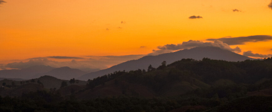 Dramatic sunset over mountain landscape. Dawn sky gold dusk time cloudscape with sunlight. Blue golden sky sunrise dramatic beautiful landscape mountain. Beautiful landscape foggy hills twilight time