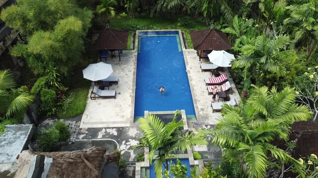 Aerial view of person swimming in a tropical resort pool