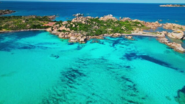 Aerial view over Spiaggia Testa del Polpo in La Maddalena. Clear blue water, sandy seabed and coastal rocks create a peaceful Sardinian beach panorama.