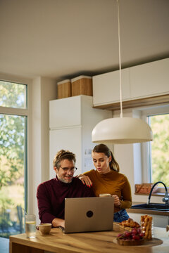 Couple working from home together in kitchen