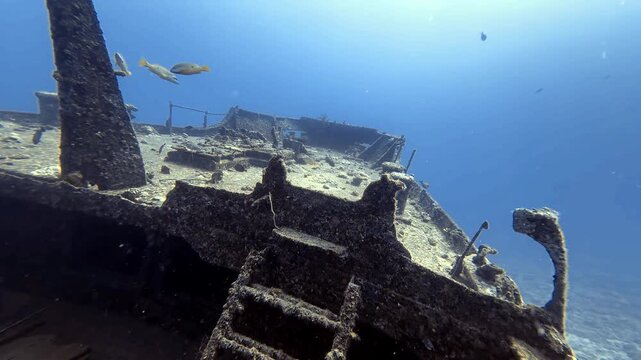 The Silver Star wreck deck and mast emerge from blue Mauritius waters, with fish above corroded structures. An atmospheric underwater scene for diving travel and maritime exploration.