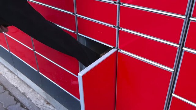 Customer hand taking out a package from a self service modern parcel locker. This innovative system simplifies e commerce shopping, offering a convenient and secure way to receive orders