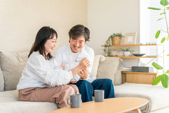 初孫との初対面に笑顔がこぼれる40代・50代の祖父母。赤ちゃんの誕生を喜ぶ幸せな家族のひととき