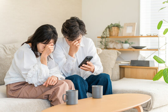 投資詐欺,誹謗中傷に悩むスマホを見る中高年の夫婦