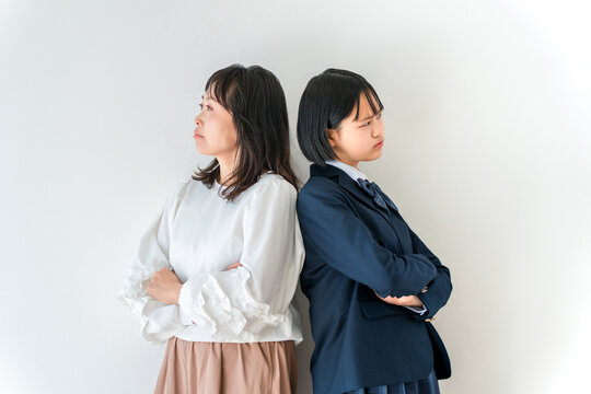 喧嘩をして背を向ける親子。意見が対立して怒る反抗期の娘と母親。