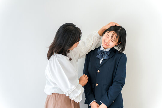 娘の頭を撫でる母親と照れくさそうにする中学生,高校生の女の子