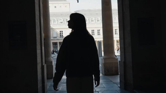 Silhouette of a young woman discovering a historic parisian courtyard