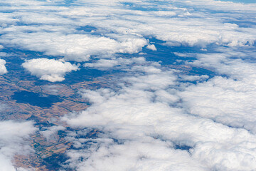 Fototapeta premium View of clouds from an airplane flying over farmland during daytime