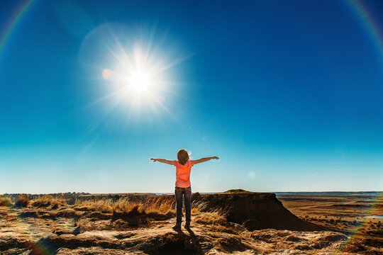 Child embracing the sun in a vast landscape