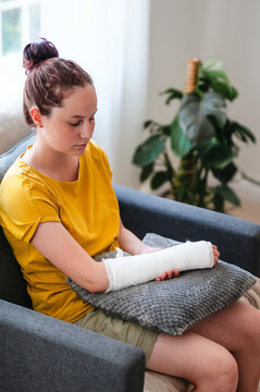 Teenage girl with injured arm in cast at home