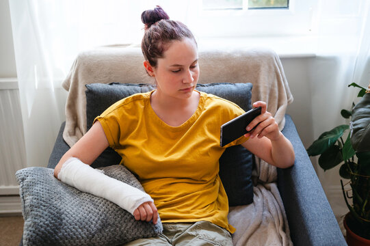 Teenage girl with injured arm in cast resting on a pillow