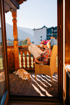 Woman and tea on balcony, view with a dog resting, mountains
