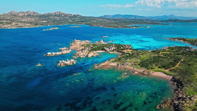 Drone view of Spiaggia Testa del Polpo coastline in La Maddalena. Turquoise bay, granite rocks and rugged shore create a peaceful Mediterranean seascape.