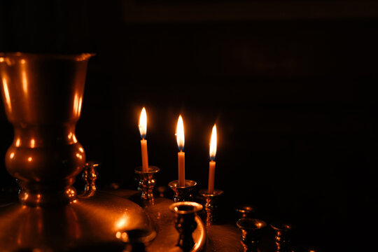 Burning church candles glow in dark religious setting