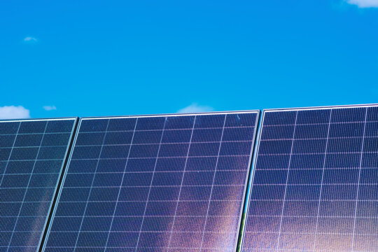 Solar panels against a clear blue sky with clouds