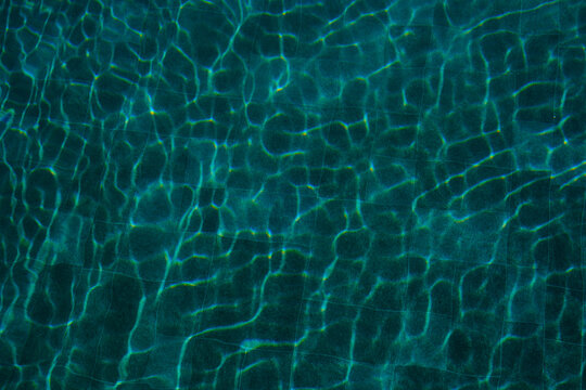 Sunlight reflecting on dark blue water surface with tile background