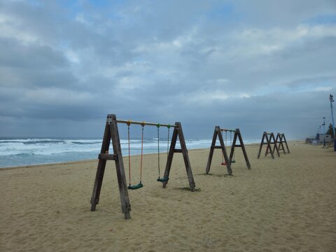 Wooden swings on an empty sandy beach under cloudy sky, east coast of Korea
