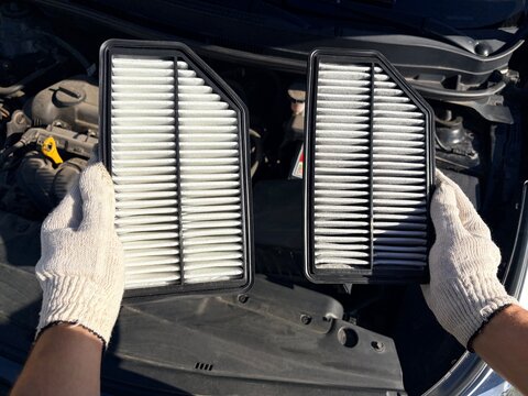Mechanic comparing new and dirty car engine air filters during maintenance service