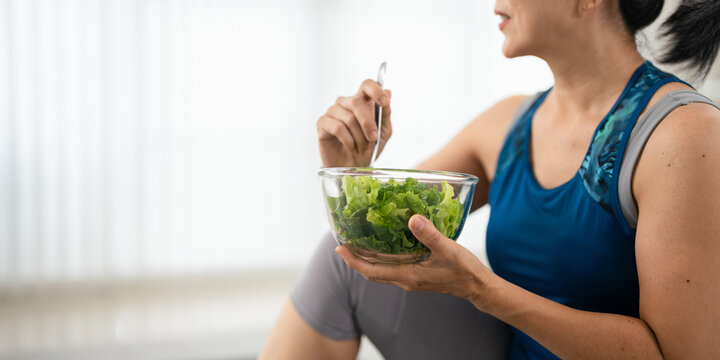 Healthy woman having salad after work out at home, sport and healthy food lifestyle concept.
