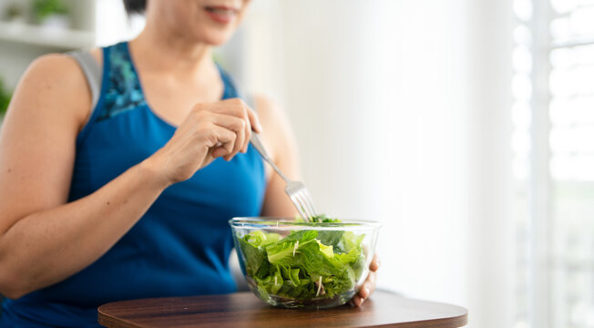 Healthy woman having salad after work out at home, sport and healthy food lifestyle concept.