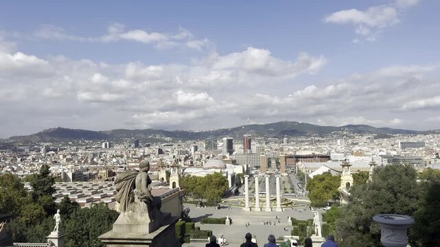 Barcelona, Spain, October 13, 2026 - Panoramic view from Palau Nacional on Montjuic hill showing statues along the grand staircase, crowds of tourists, Arenas de Barcelona, and the cityscape.